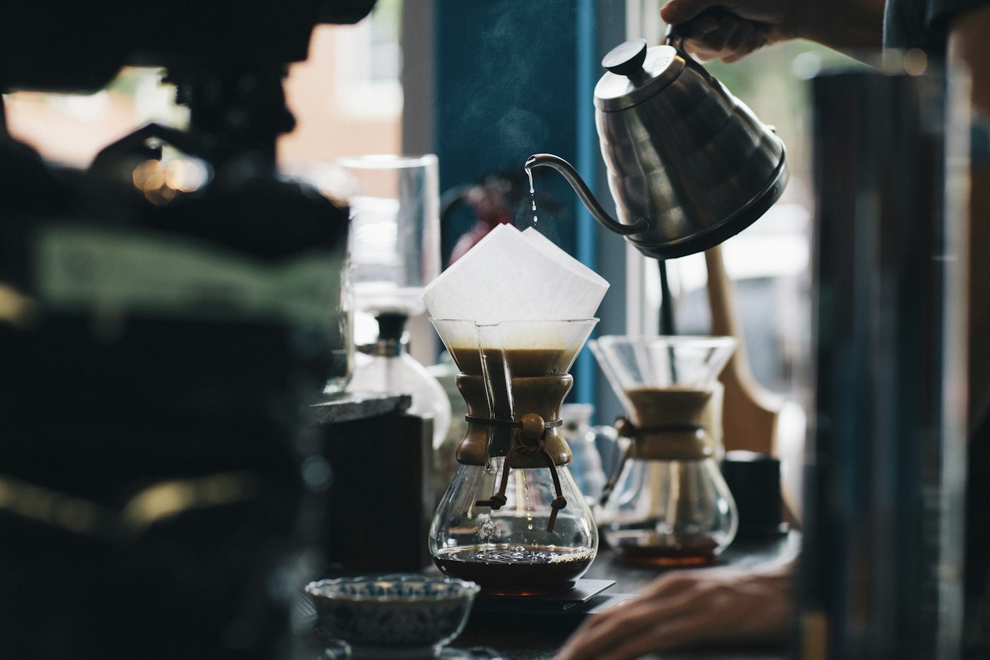 A barista pouring hot water over a pour-over coffee